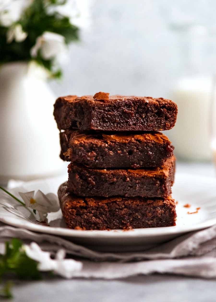 Stack of Flourless Chocolate Brownies (gluten free) slices with milk and flowers in the background