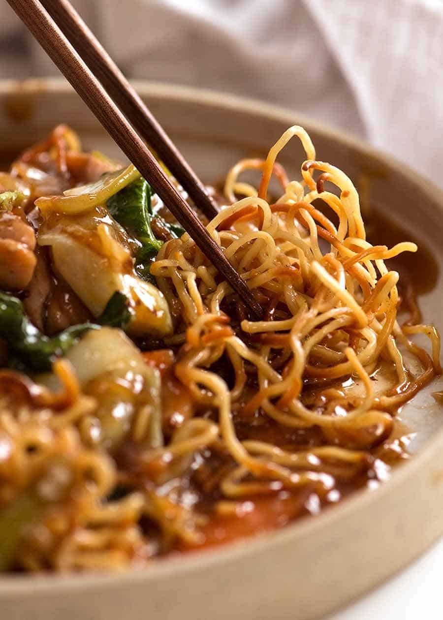 Close up photo of chopsticks picking up Chinese Crispy Noodles (Chow Mein)
