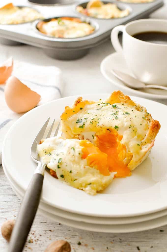 Muffin Tin Breakfast Croque Madame Toastie Cup on a white plate, cut open with runny egg yolk running out.