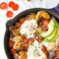 Chorizo Breakfast Hash with crispy smashed potatoes and eggs in a cast iron skillet with avocado on the side.