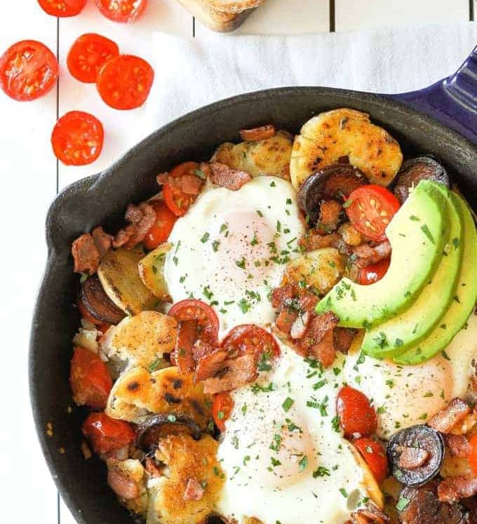 Chorizo Breakfast Hash with crispy smashed potatoes and eggs in a cast iron skillet with avocado on the side.