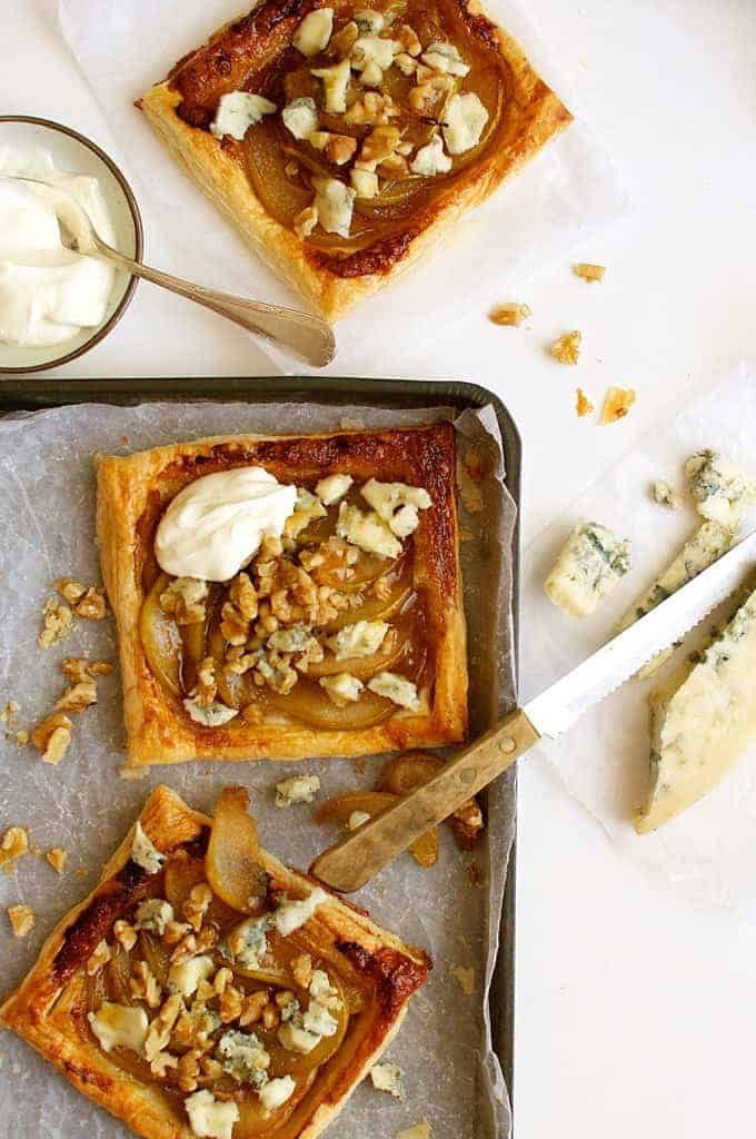 Caramelized Pear and Blue Cheese Tarts on a tray with a block of gorgonzola cheese