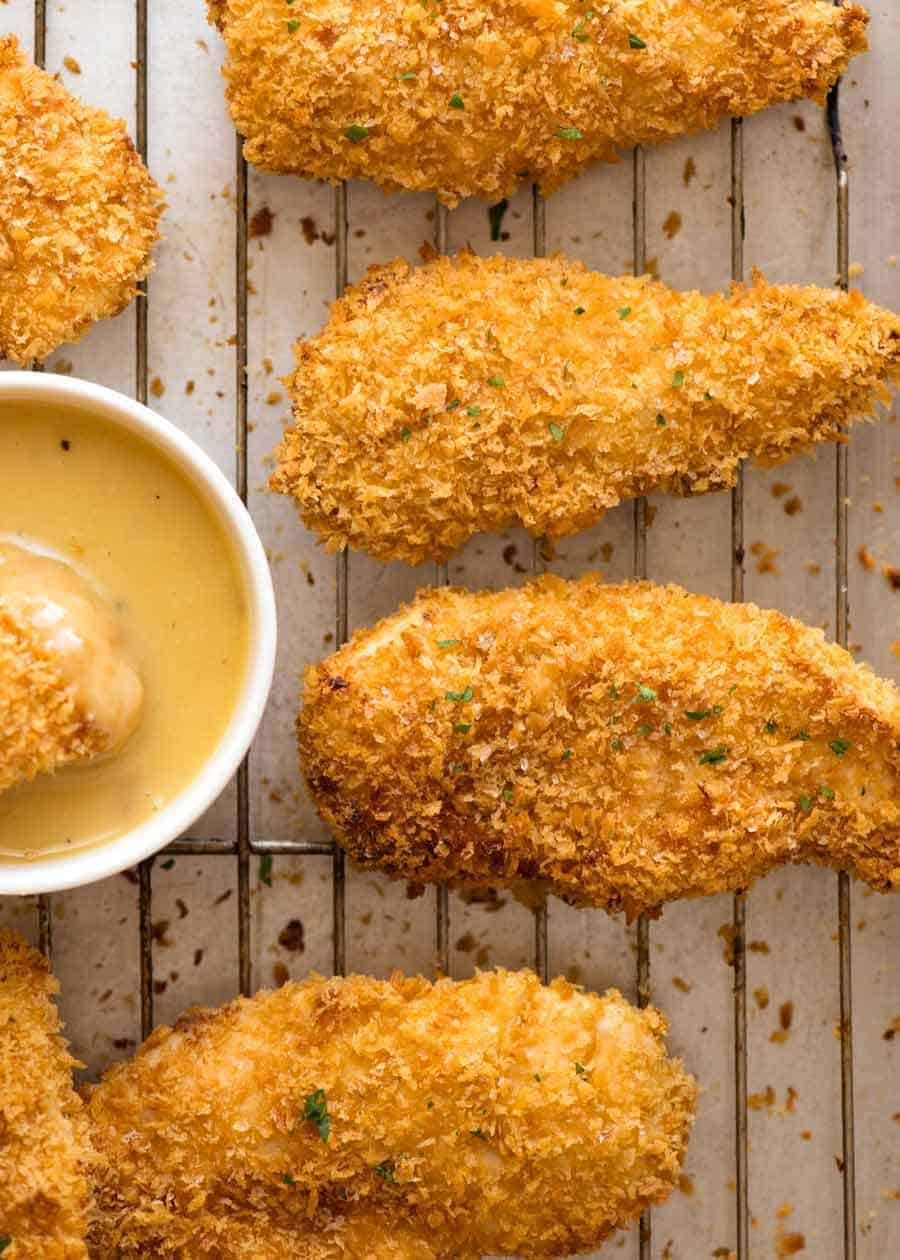 Crunchy Baked Chicken Tenders on a tray with a Honey Mustard Dipping Sauce on the side, fresh out of the oven