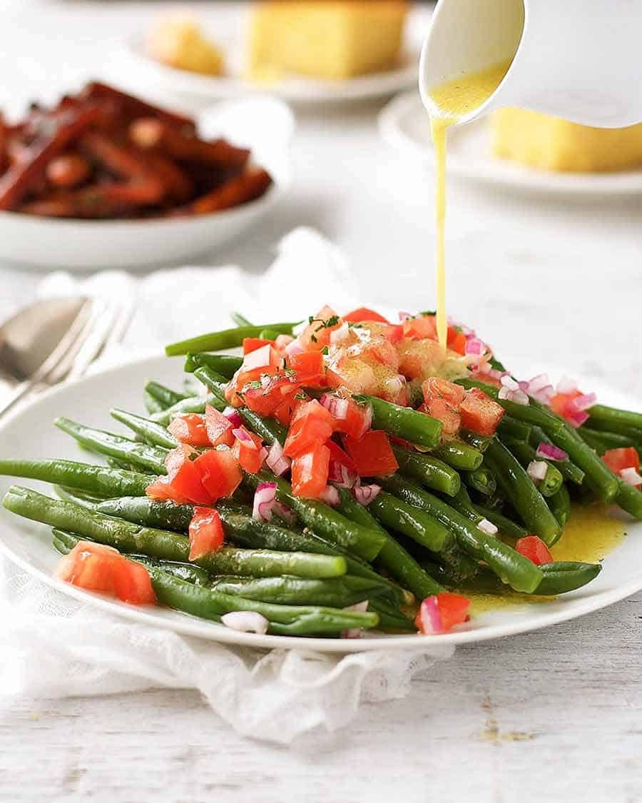 Pouring lemon dressing over green bean salad