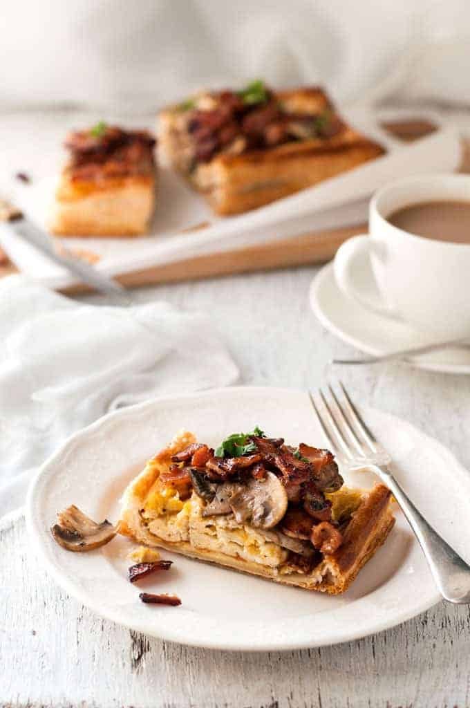 Slice of Bacon, Egg and Mushroom Tart on a white plate, ready to be eaten.