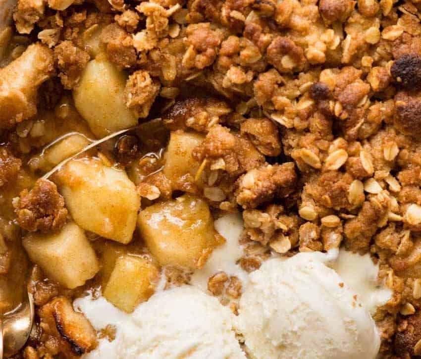 Overhead photo of Apple Crumble showing the warm, cinnamon apple filling, topped with scoops of vanilla ice cream