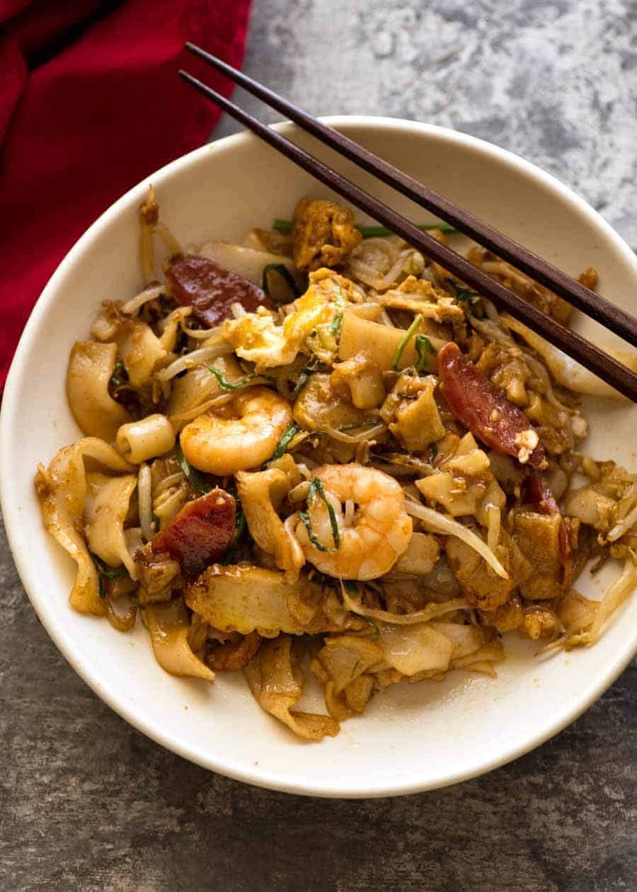 Char Kway Teow in a rustic white bowl with chopsticks resting on the side, ready to be eaten