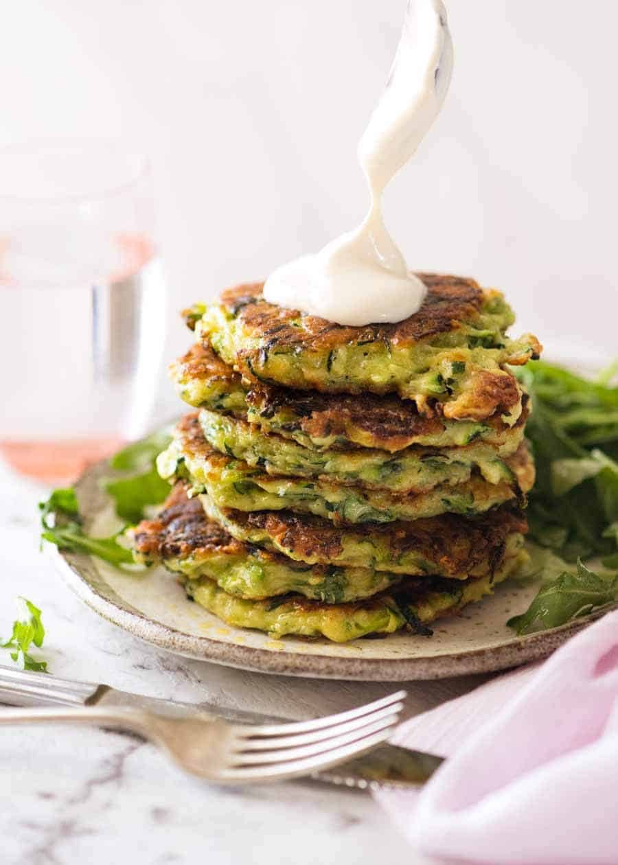 Dolloping sour cream on a stack of Crispy Zucchini Fritters