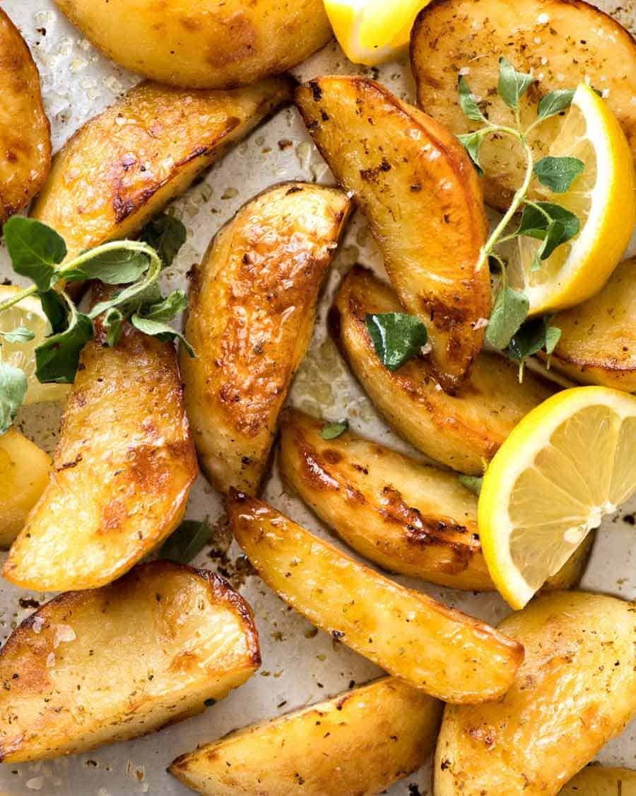 Close up of Greek Lemon Potatoes garnished with fresh oregano and lemon wedges