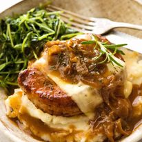 French Onion Smothered Pork Chops on mashed potato with a side of sautéed snow pea sprouts