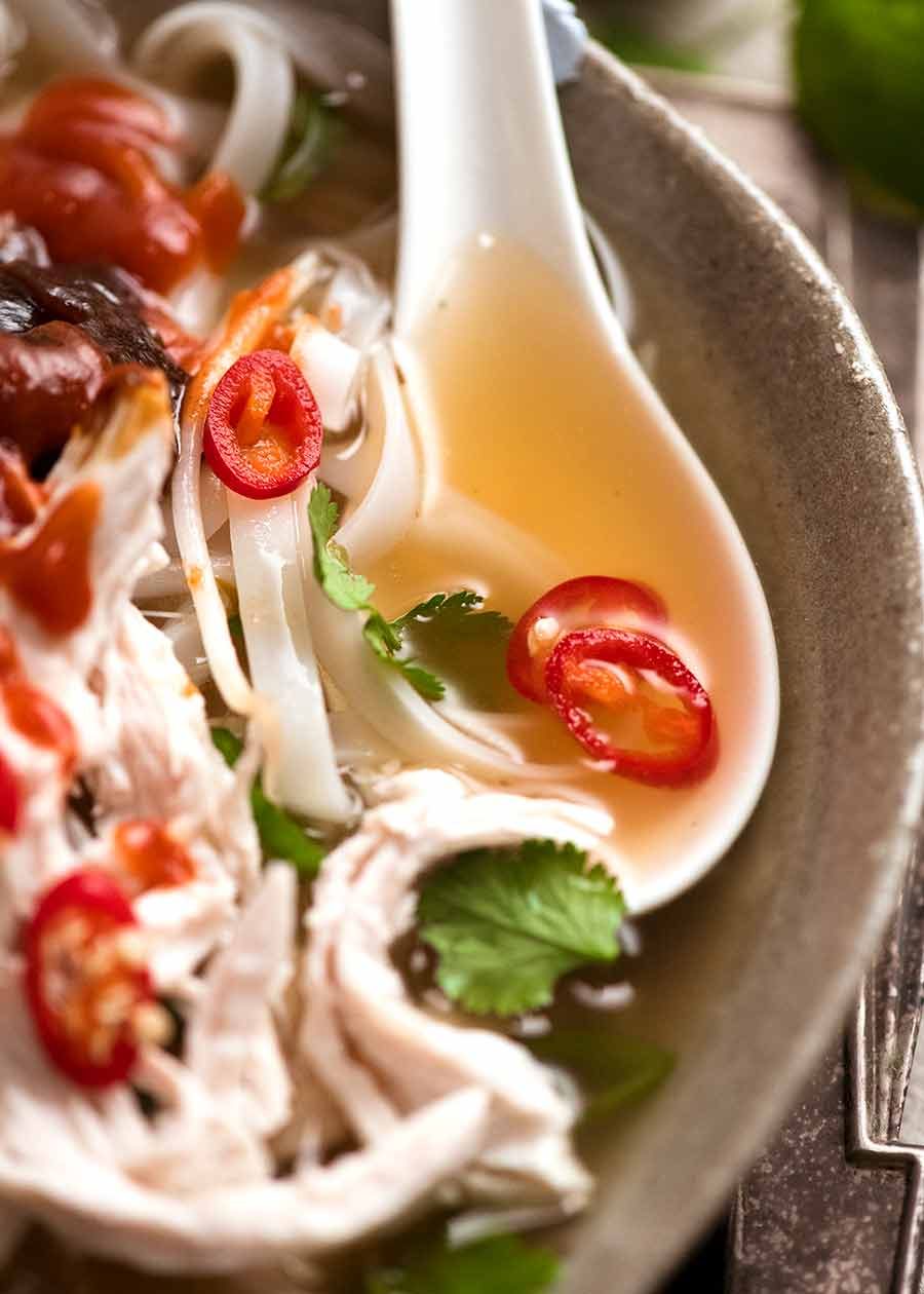 Close up of spoon scooping up broth of Chicken Pho