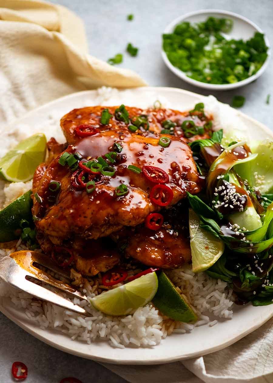 Pile of Asian Chilli Chicken served over rice with steamed asian greens on the side