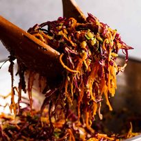 Wooden spoons tossing Cabbage and Carrot Thoran-style salad (Indian Salad)