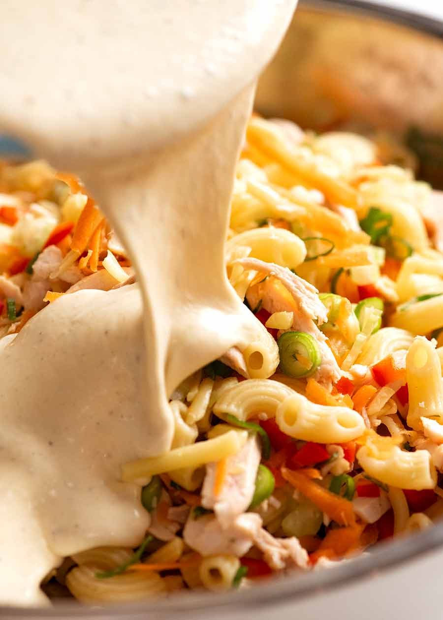 Creamy Dressing being poured over Chicken Pasta Salad