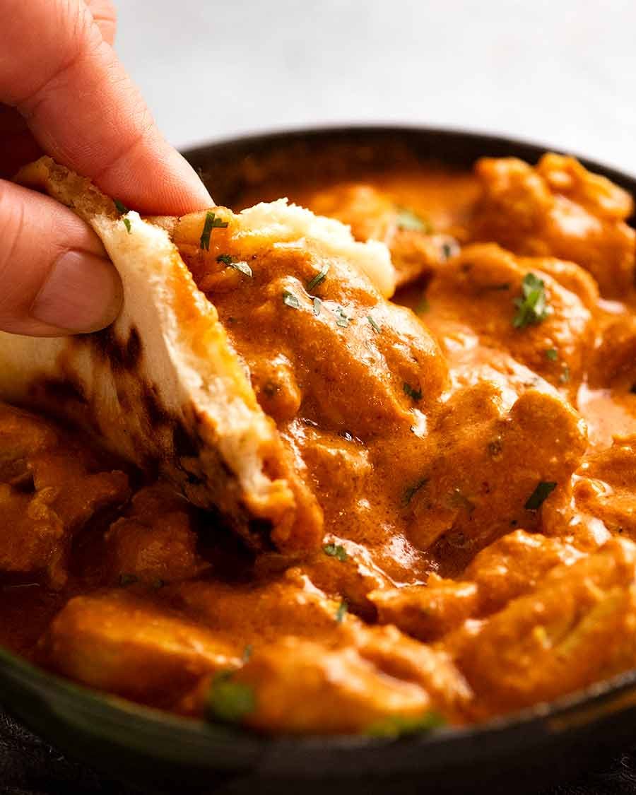 Scooping up Butter Chicken with fresh homemade naan