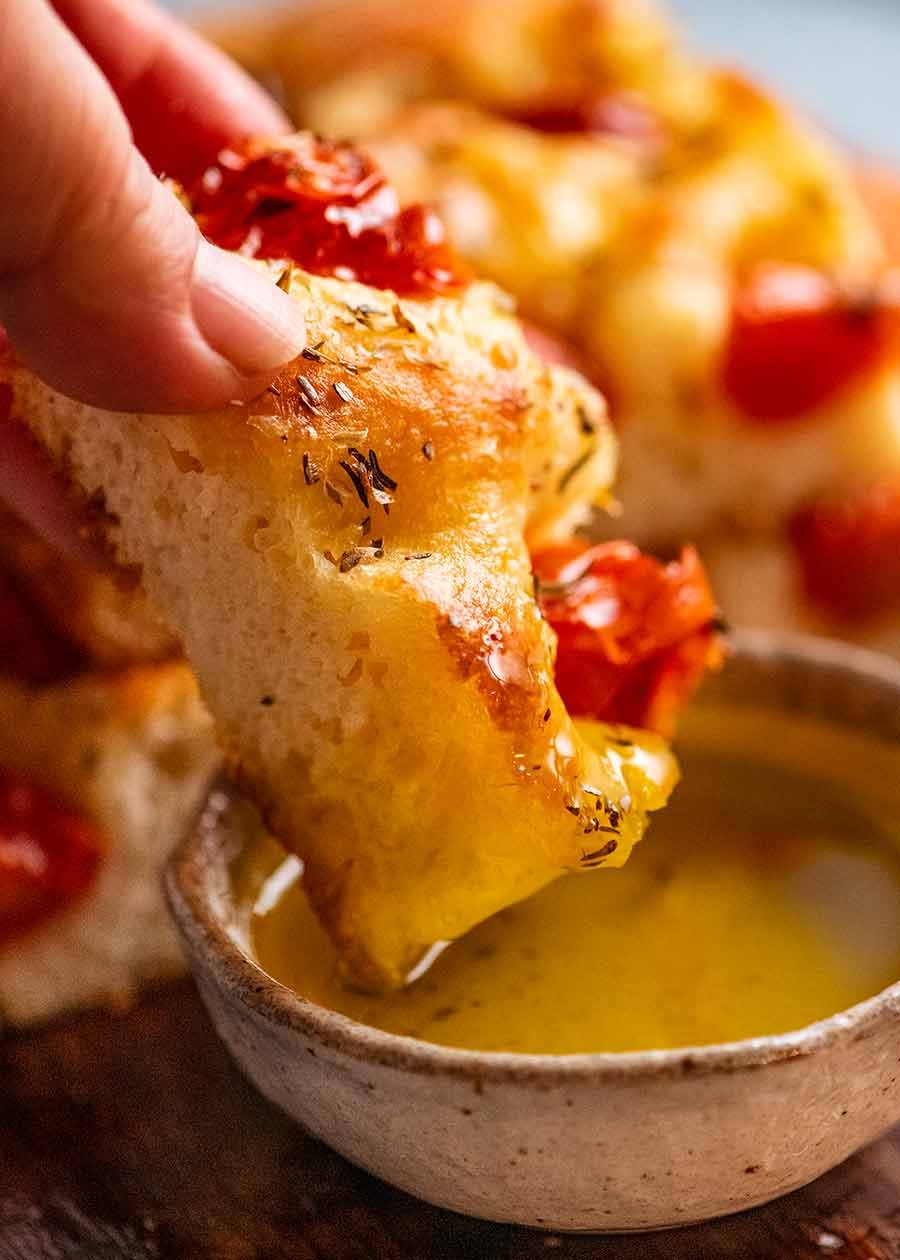 Dipping tomato focaccia into olive oil