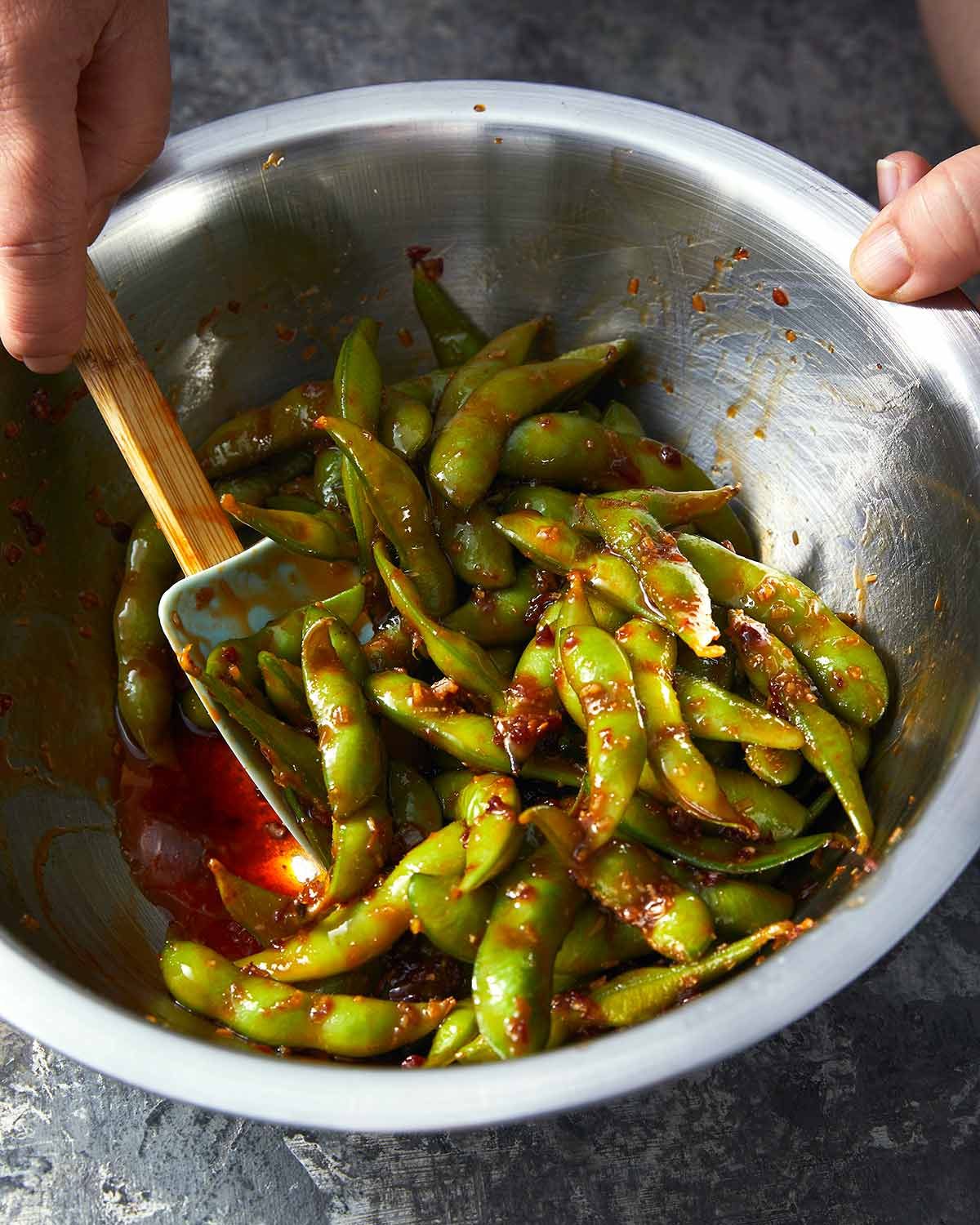 Tossing Spicy edamame in a bowl
